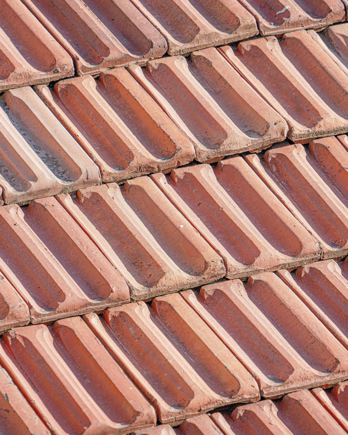 Close-up of weathered terracotta roof tiles laid in even rows.