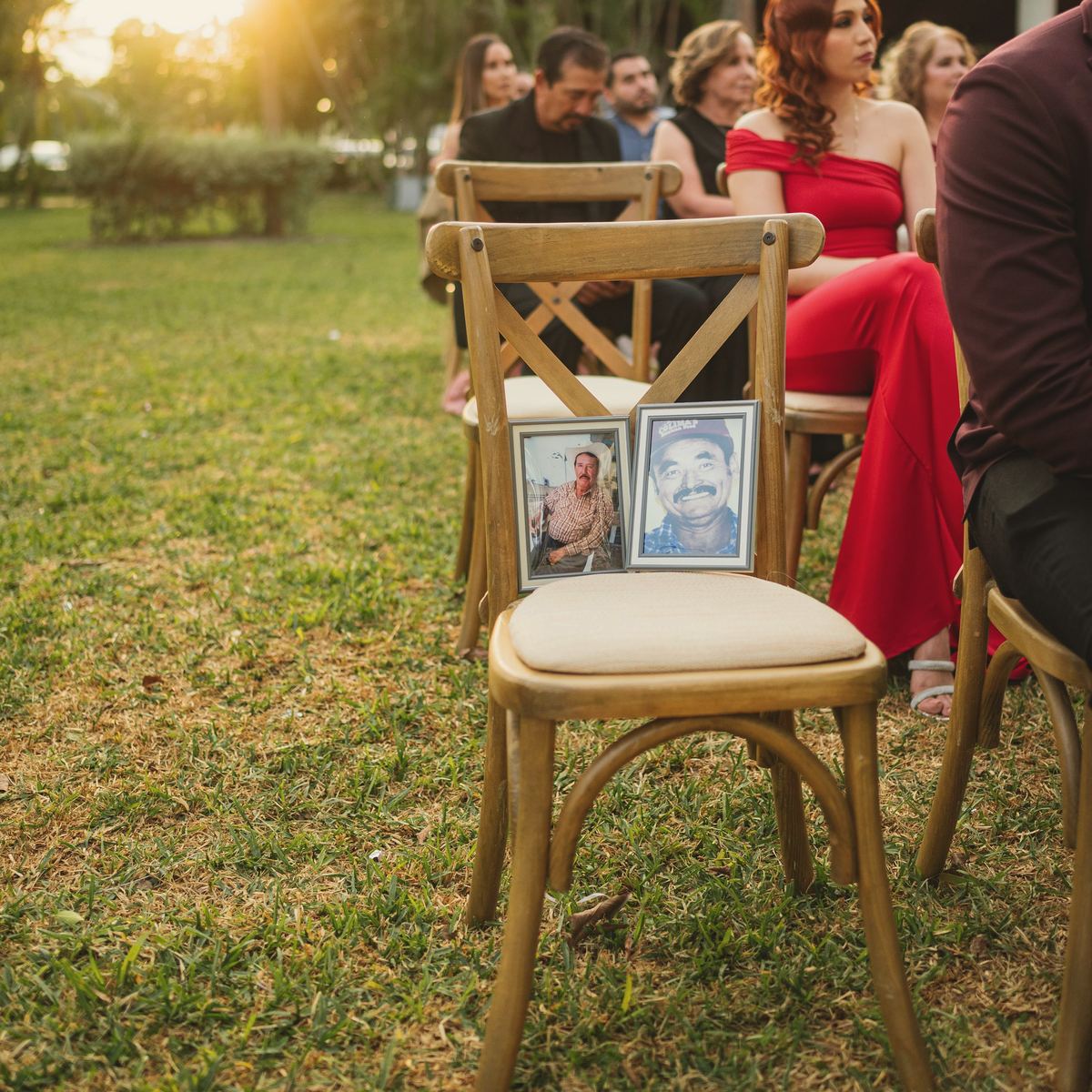 An empty chair in the front row holding two framed photographs of family who couldn't be there.