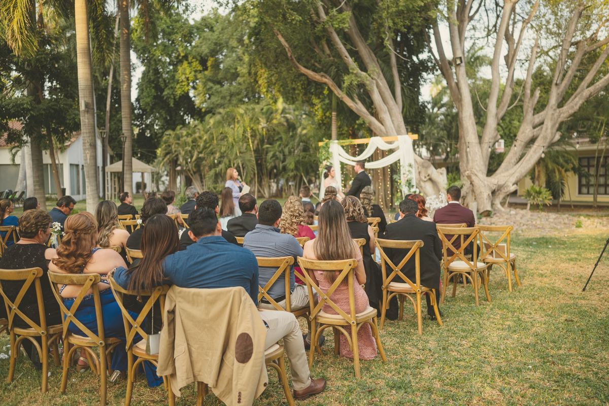 Guests on timber chairs under the big shade trees, watching the ceremony.