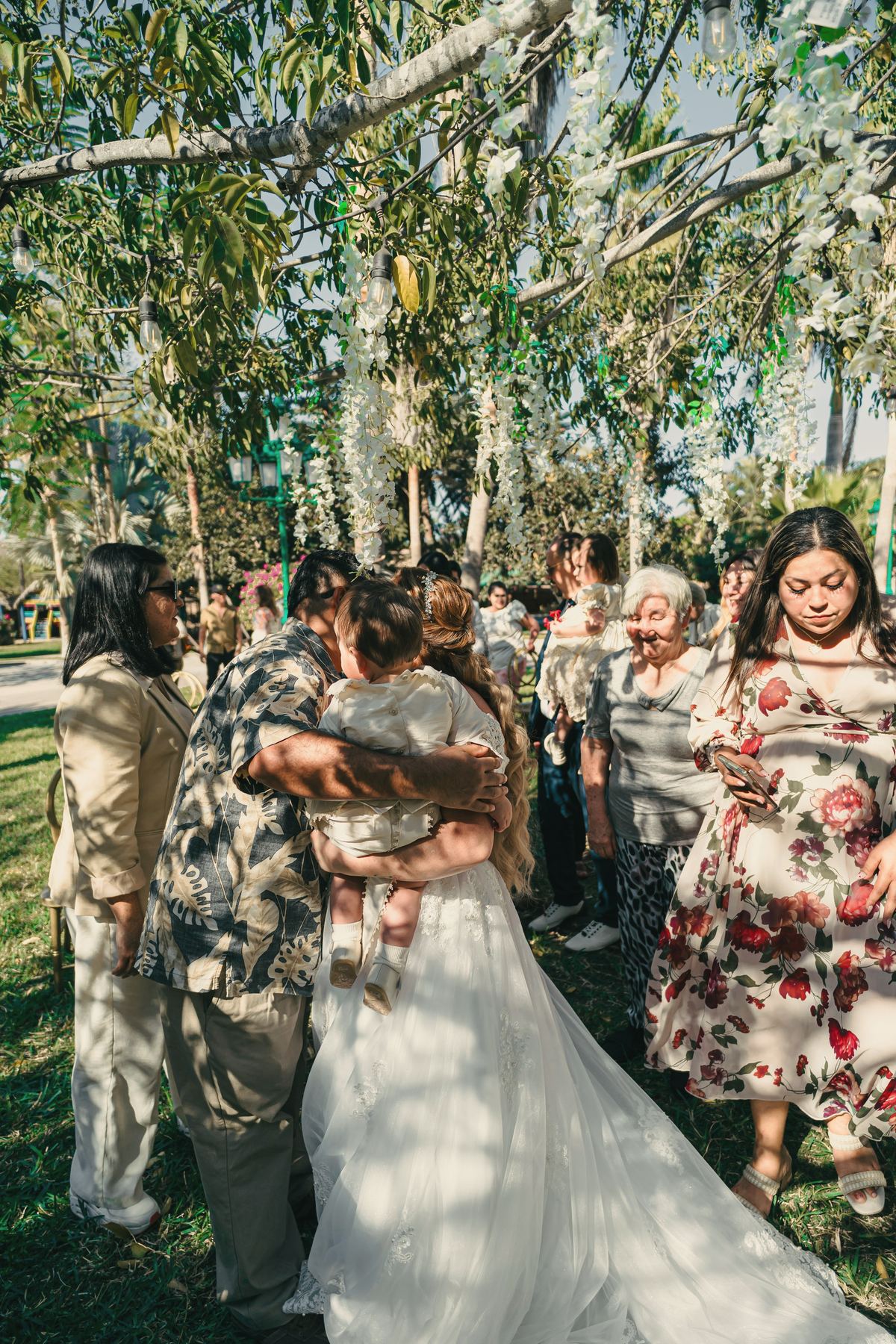 Mara in her gown being hugged by guests among the tables in the garden.