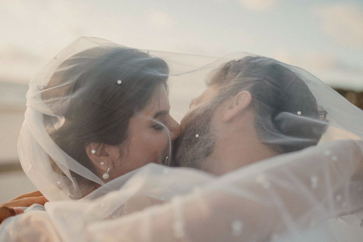 Anouk and Ben kissing inside her veil as the wind lifts it.