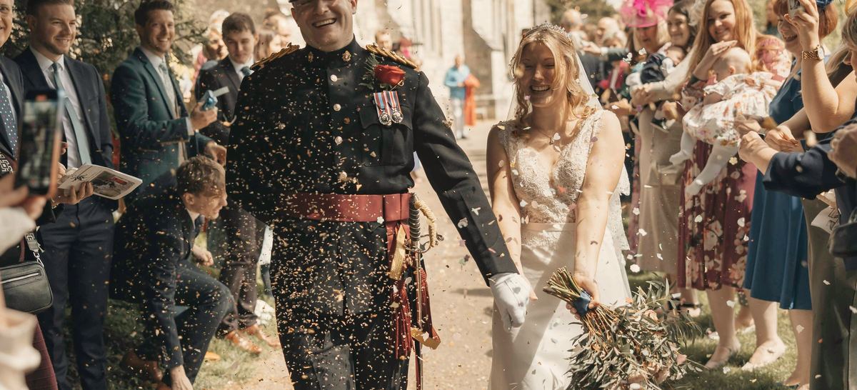 Hollis and June walking out through a crowd of guests throwing confetti.