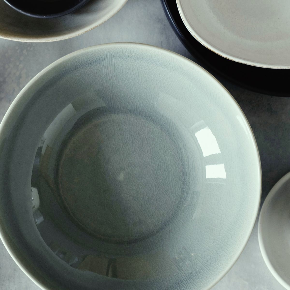 A wide grey-green serving bowl from above, the glossy glaze darker where it pools in the centre.