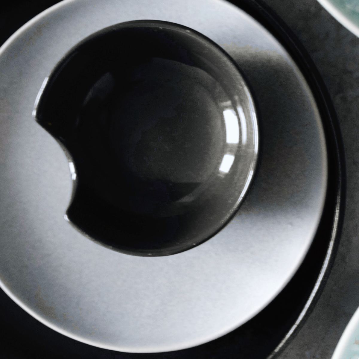 A glossy near-black rice bowl from above, resting on a pale plate.