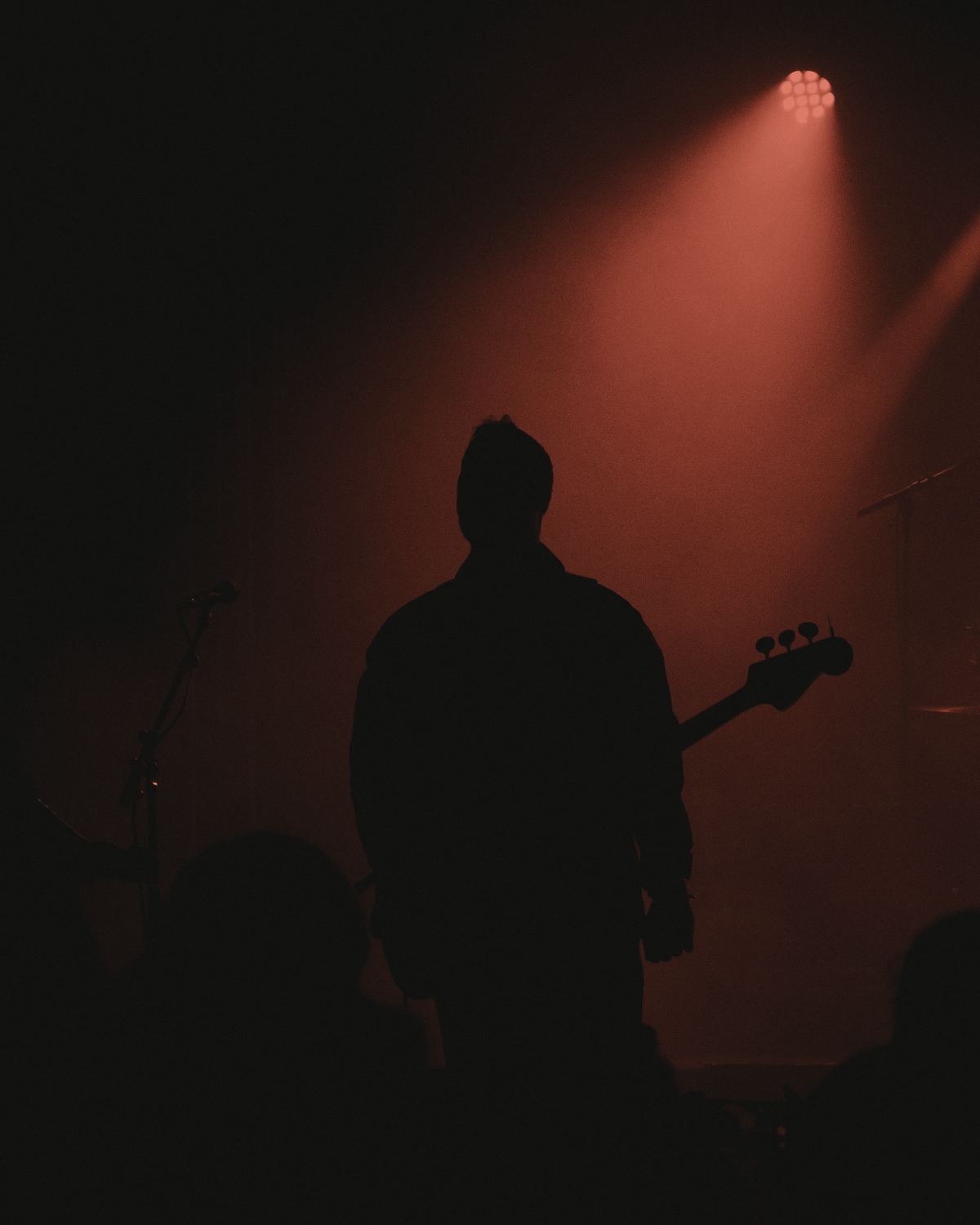 A bass player in silhouette under a single spotlight.